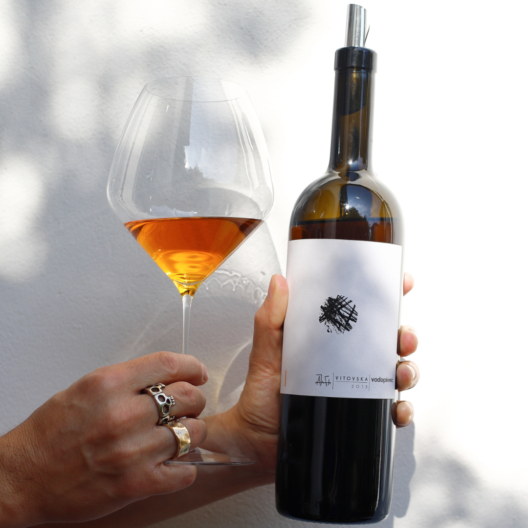 オレンジワインの哲学・ヴォドピーヴェッツのワインと注がれたグラスを手に持って